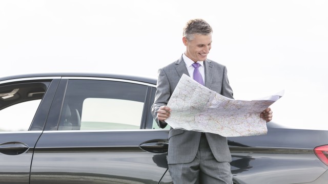 Betriebsrentenstärkungsgesetz Ein Mann steht lächelnd vor seinem Auto und blickt in einer Straßenkarte